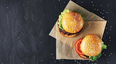 Top view of 2 burgers sitting on a black top